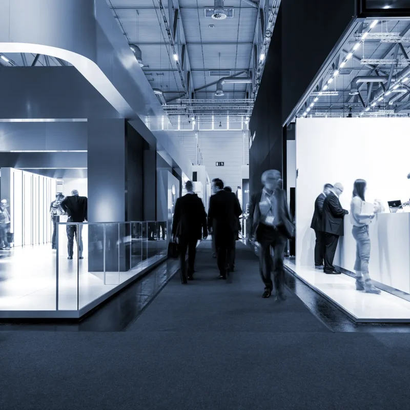 Persone che camminano tra gli stand di una fiera in un padiglione climatizzato con unità di trattamento aria a noleggio Airtech