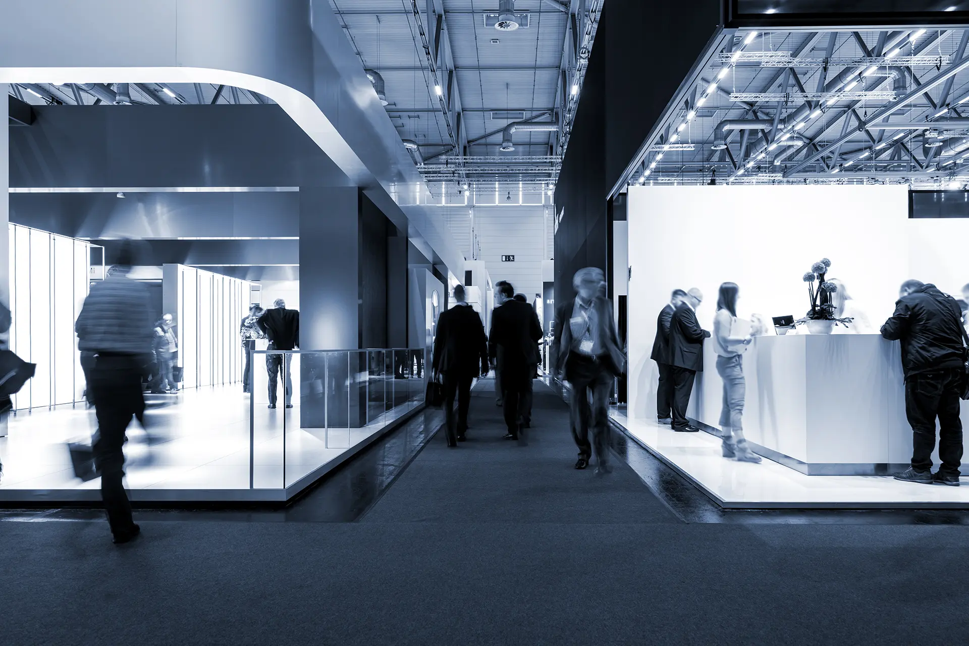 Persone che camminano tra gli stand di una fiera in un padiglione climatizzato con unità di trattamento aria a noleggio Airtech